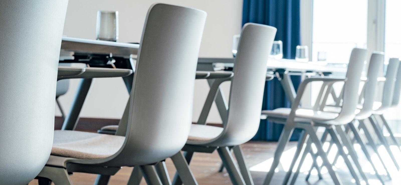 Ein Konferenzraum mit weißen Stühlen und einem Tisch.
