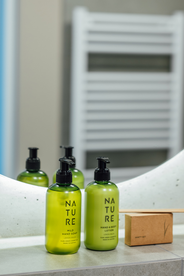 Galeriebild VEMA_2712.jpg Zwei Flaschen mit grüner Seife und Lotion sowie ein kleiner Karton auf einem Badezimmerwaschtisch.
