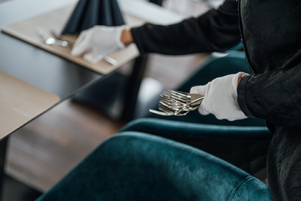 Galeriebild VEMA_3171.jpg Ein Kellner mit Handschuhen deckt einen Tisch mit Besteck in einem eleganten Restaurant.