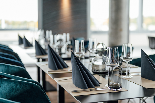 Galeriebild VEMA_3241.jpg Elegant gedeckter Tisch in einem Restaurant mit schwarzen Servietten, Gläsern und stilvollem Geschirr.
