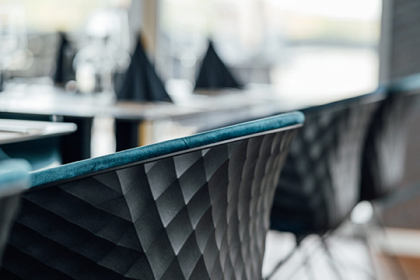 Galeriebild VEMA_3324.jpg Ein Blick auf elegante Stühle mit einem strukturierten schwarzen Bezug und blauen Akzenten in einem Restaurant.