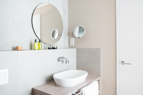 Galeriebild VEMA_3586.jpg Ein modernes Badezimmer mit Waschbecken, Spiegel und dekorativen Flaschen auf einem Regal.