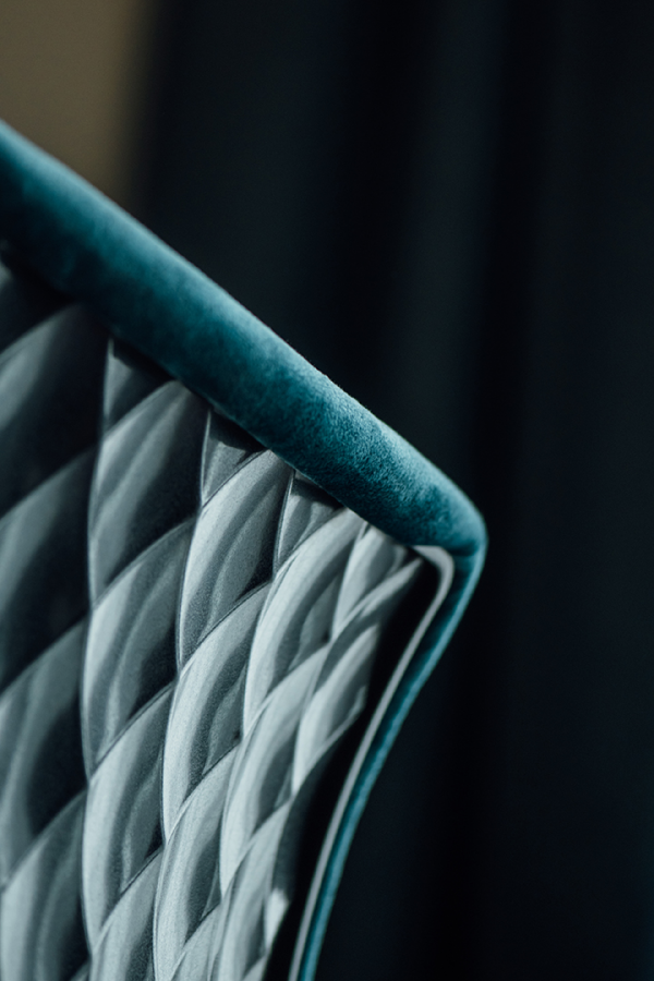 Galeriebild VEMA_3752.jpg Ein detailreicher Aufnahm eines gepolsterten Stuhls mit einer strukturierten, teal-farbenen Oberfläche.