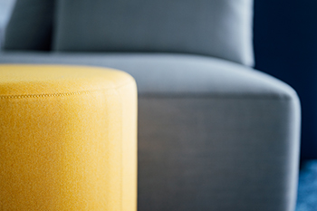 Galeriebild VEMA_4417.jpg Ein gelber Hocker vor einer grauen Couch.