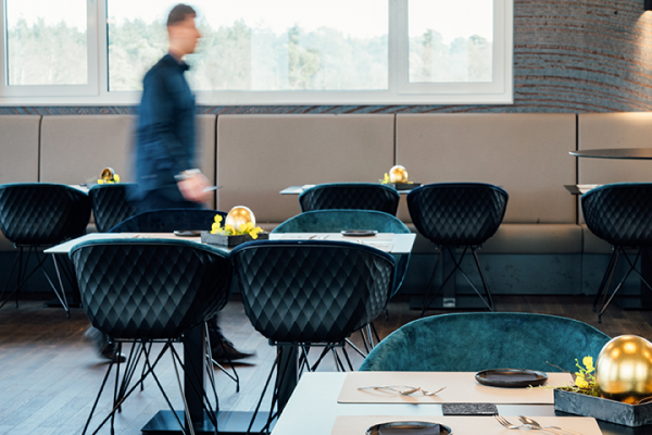 Galeriebild VEMA_5142.jpg Ein modernes Restaurant mit eleganten Stoffmöbeln und einem verschwommenen Menschen, der sich bewegt.