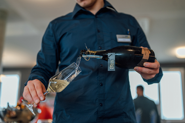 Galeriebild VEMA_6160.jpg Ein Kellner schenkt Sekt in ein Glas ein.