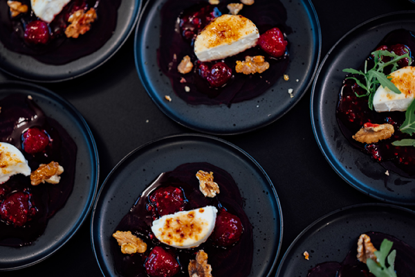 Galeriebild VEMA_8394.jpg Sechsm schwarze Teller mit Himbeeren, Walnüssen, einer cremigen weißen Schicht und Karamell-Akzenten.