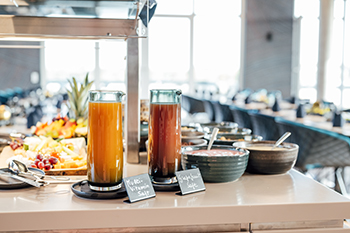 Galeriebild VEMA_8439.jpg Ein Buffet mit Getränken in Gläsern, darunter Säfte, und Schalen mit verschiedenen Beilagen.