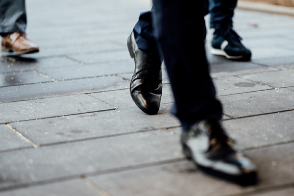 Galeriebild VEMA_8492.jpg Drei Personen gehen auf einem Gehweg, ihre Schuhe sind sichtbar.