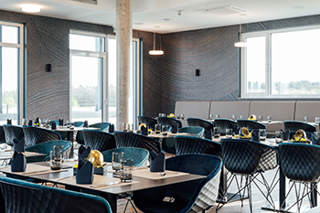 Galeriebild VEMA_8611.jpg Ein modernes Restaurant mit Tischen, stilvollen Stühlen und großen Fenstern.