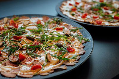 Galeriebild VEMA_9146.jpg Zwei Teller mit Carpaccio, garniert mit Rucola, Kirschtomaten und Mandelscheiben.