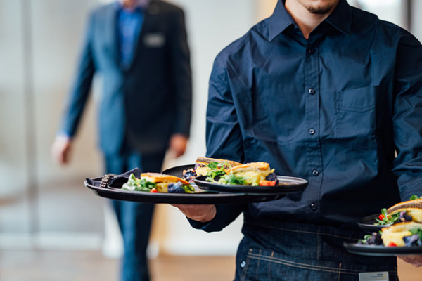 Galeriebild VEMA_9539.jpg Ein Kellner trägt mehrere Teller mit Essen in einem modernen Restaurant.